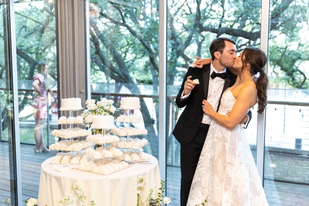 Bride and groom kissing next to their cake table at The Grove Houston wedding.
