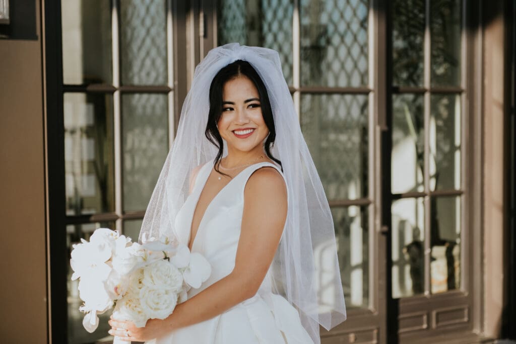 Bride posing with an all-white wedding bouquet.